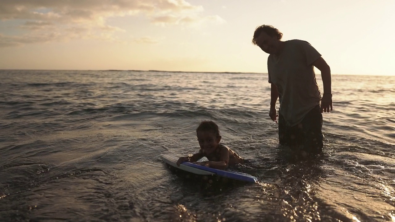 快乐男孩和他爸爸在沙滩上玩人体滑板视频下载