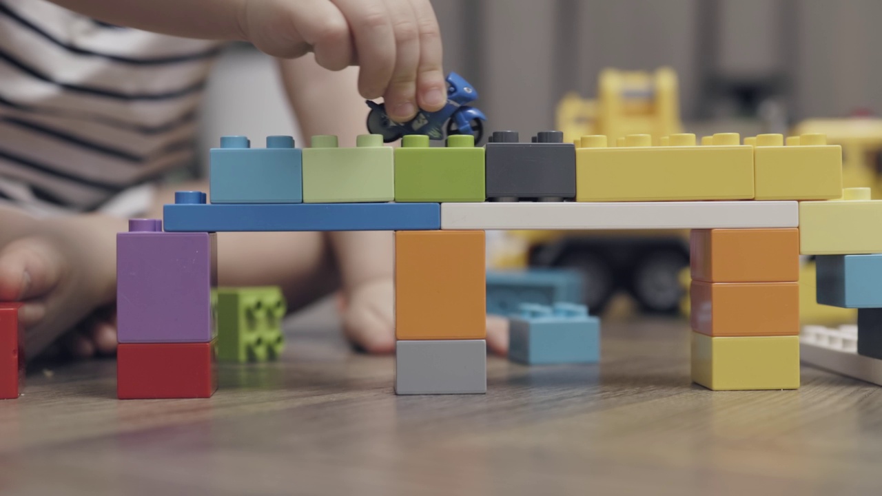 无法辨认的孩子的手在室内玩彩色的塑料积木视频下载