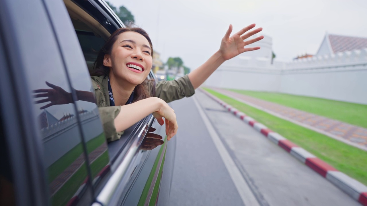 亚洲美女旅行者打开车窗面对外面的空气。有魅力的年轻女游客背包旅行在美丽的城市，花时间自驾游在泰国的假期旅行。视频下载