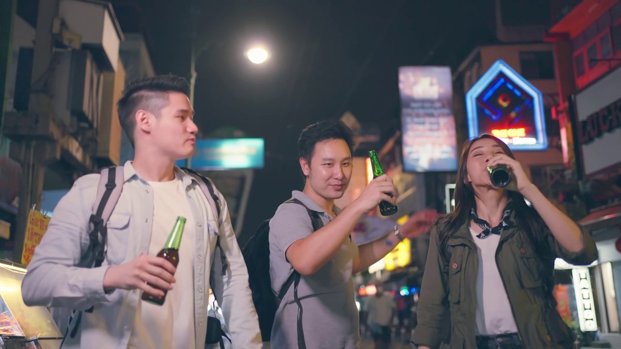 一群喝着酒、喝醉了的人在一起聚会。在城市旅游的青年男女在假期里一起度过假期，在漆黑的夜晚手拿一瓶啤酒在路上。视频素材