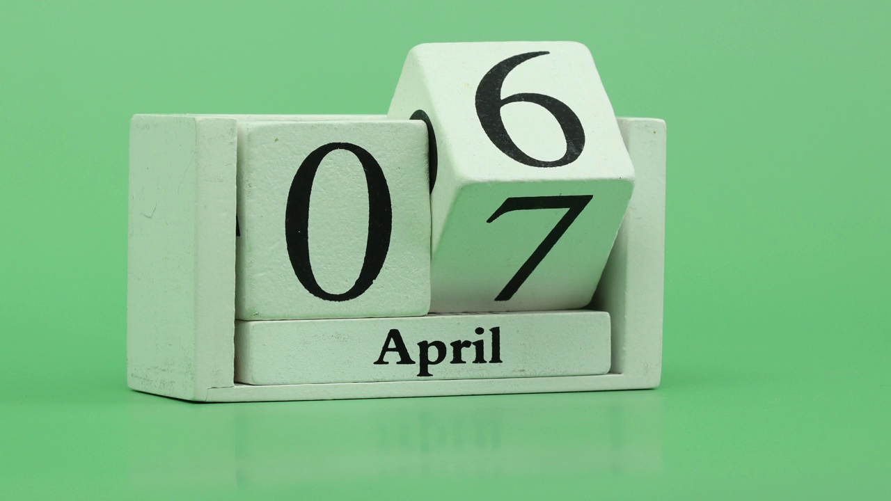 四月月历4K定格动作快节奏的时间在一个月期间由手工木历日期月和日在一个木制的桌子上视频素材