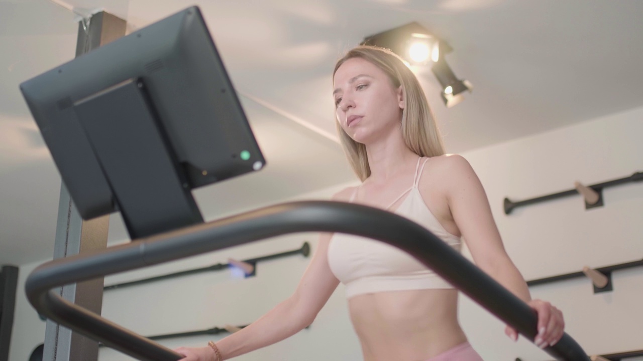 健身女孩在现代健身工作室锻炼。女人走在跑步机上…视频素材