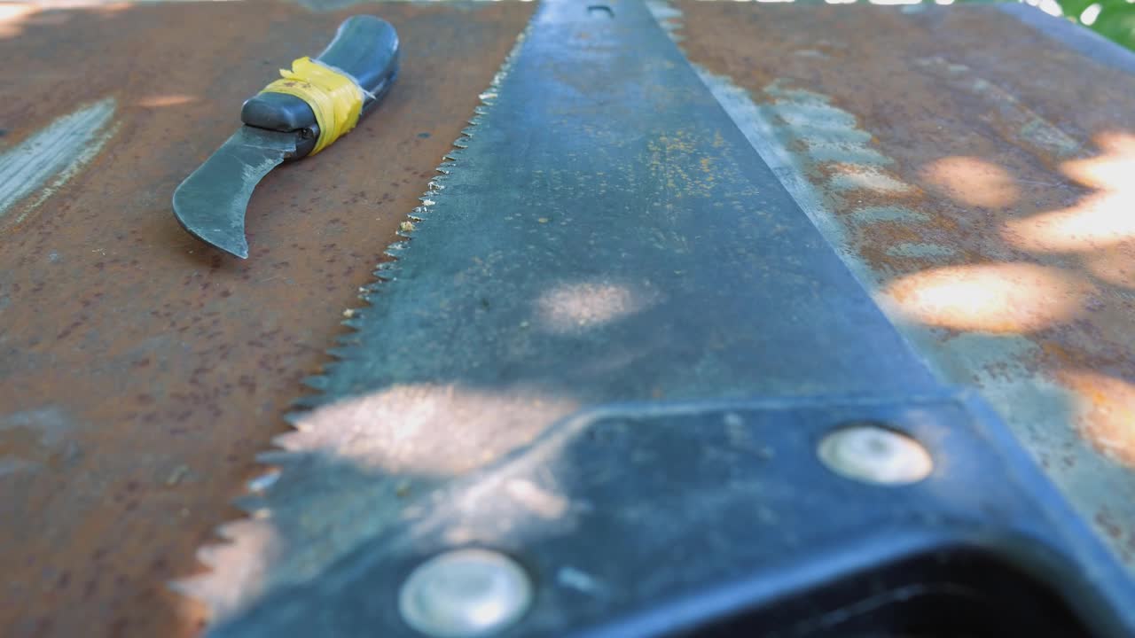 木工用的技术刀和木工用的旧手锯。工具摆放在生锈的钢制桌子上视频下载