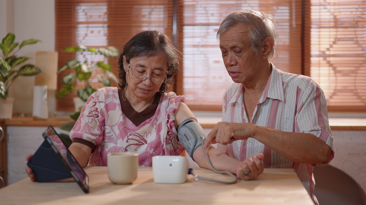 老年亚洲病人妇女正在协助成熟的成年男子与远程健康访问的笔记本电脑，而视频会议与男性医生视频素材
