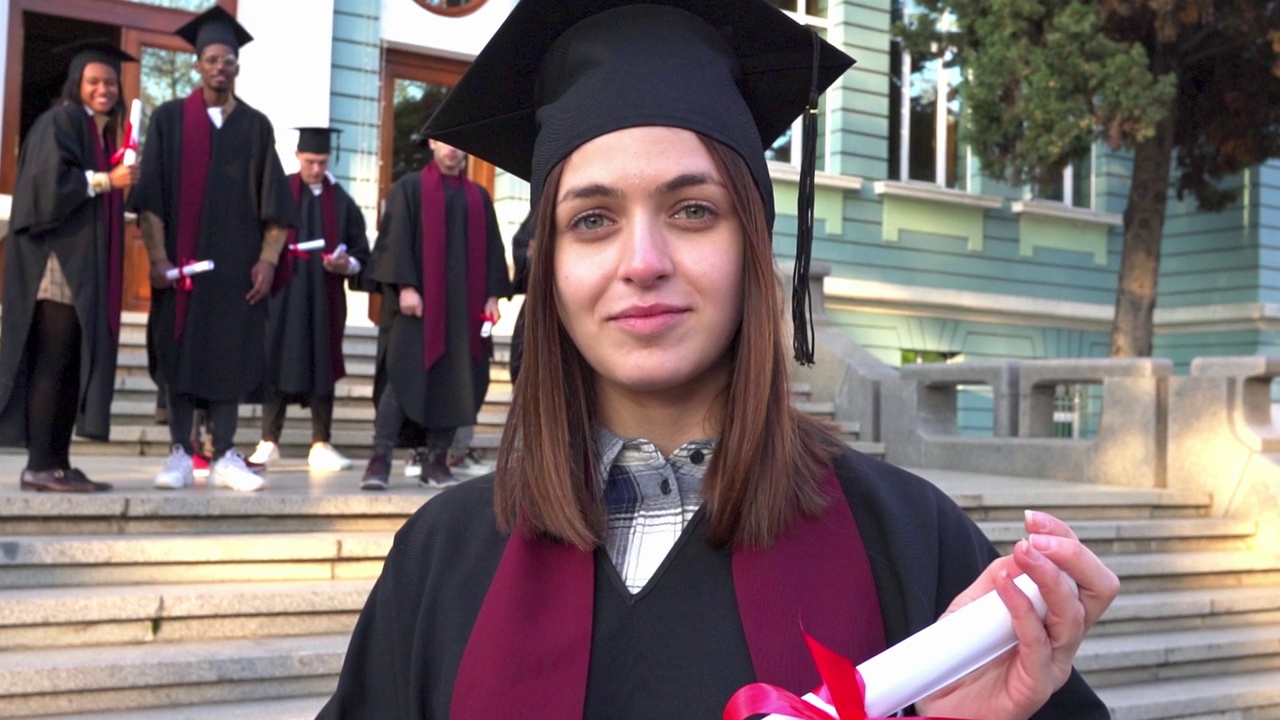一名女学生手持文凭站在大学台阶上的肖像视频素材