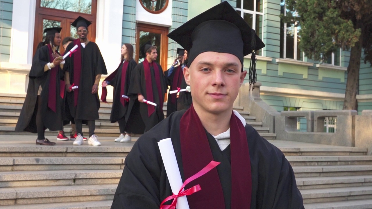 一个男学生拿着学位站在大学台阶上视频素材