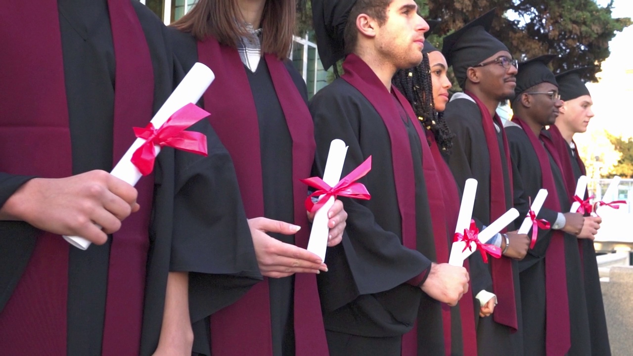 身穿学士服和毕业钵的毕业生站成一排视频素材