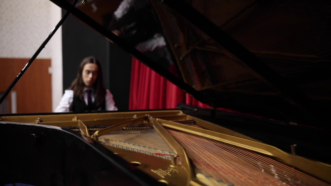 身着燕尾服，头发浓密的钢琴家在三角钢琴上练习奏鸣曲演奏。视频下载