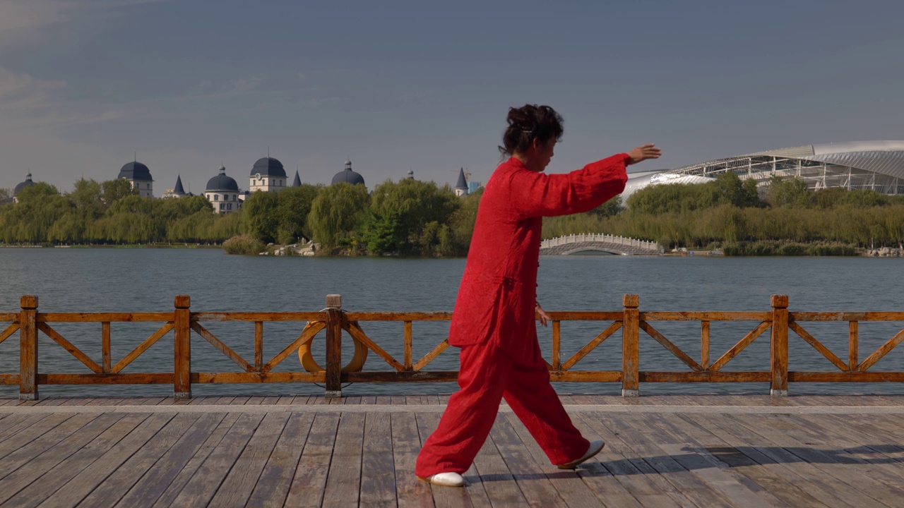 一个女人在湖边练习太极拳。视频素材