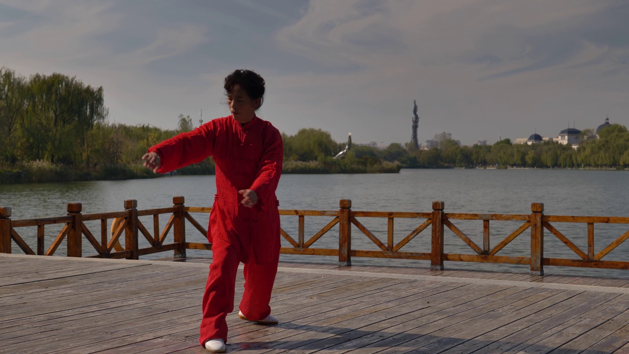 一个女人在湖边练习太极拳。视频素材