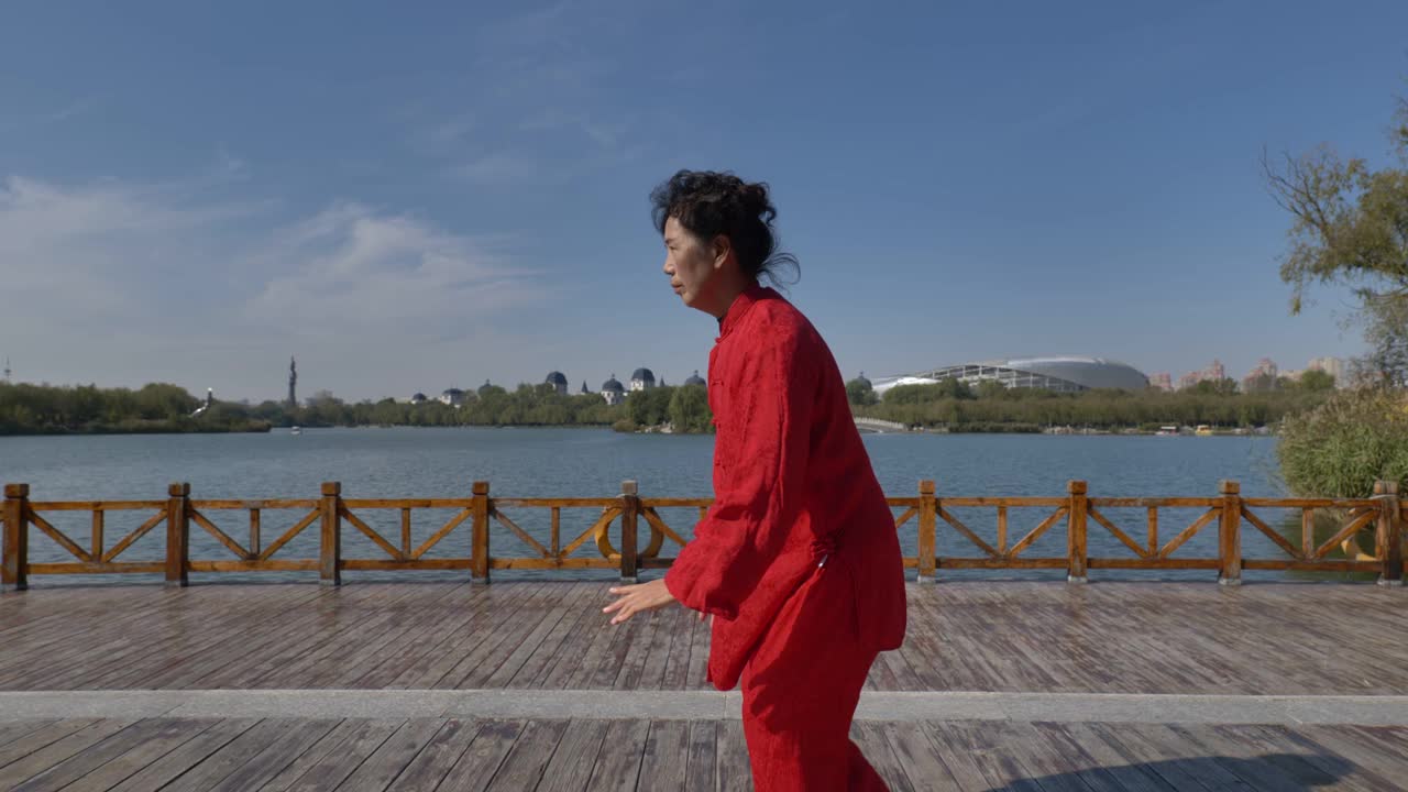 一个女人在湖边练习太极拳。视频下载