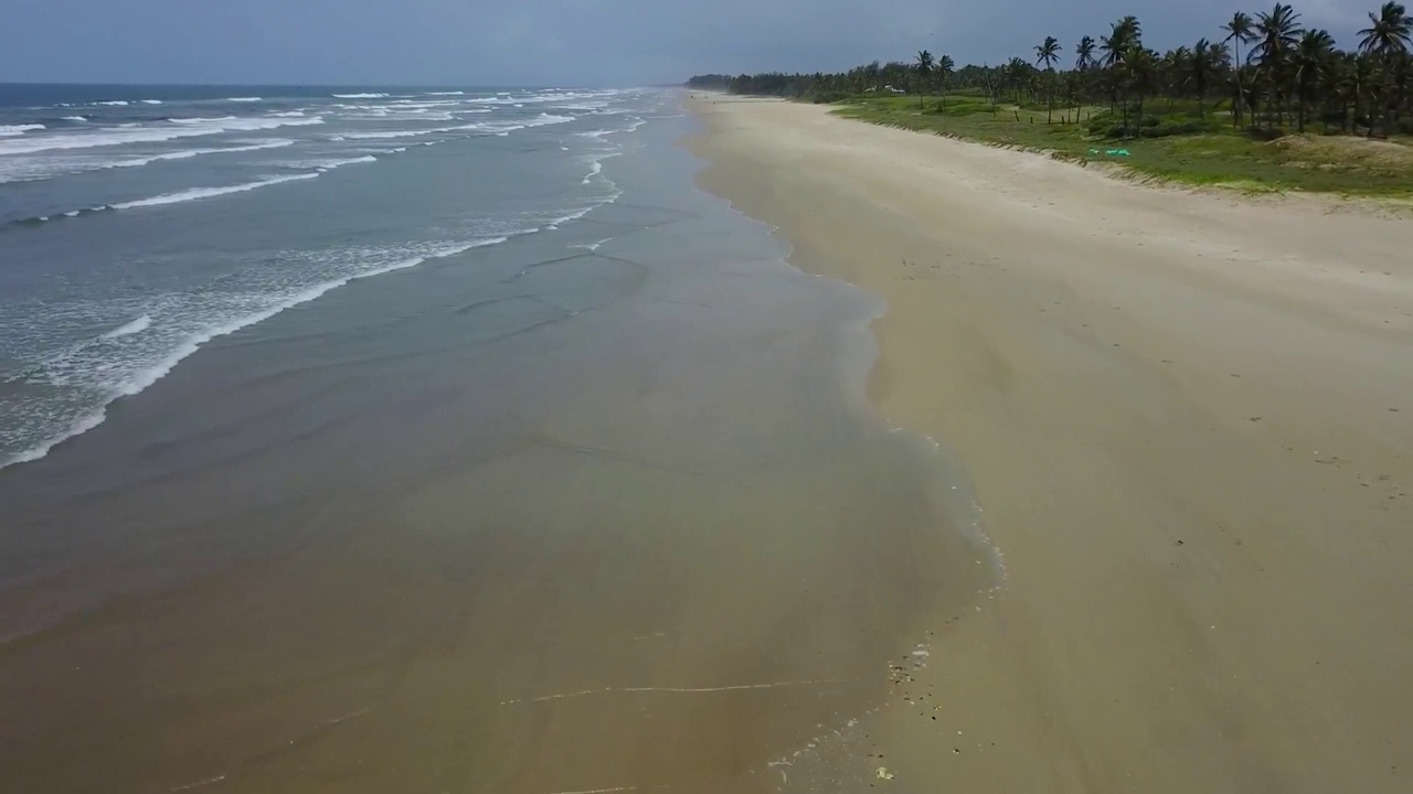 鸟瞰图，蓝绿色的海浪拍打在沙滩上。金色的沙滩与深蓝色的海水和泛着泡沫的波浪相遇。视频素材