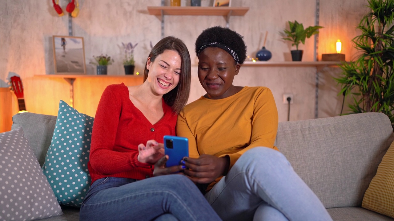 两个女性朋友一边用手机看自拍照，一边大笑视频素材