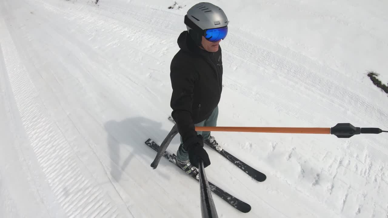 快乐的男性滑雪者自拍。T形杆滑雪缆车将滑雪者拉上斜坡视频下载
