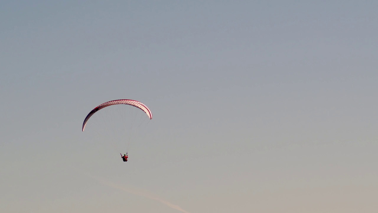 独自滑翔伞在日落时，在清澈的彩色天空中飞得很高。在阳光明媚的日子里，在空中滑翔，极限运动视频素材