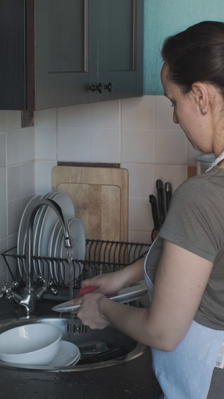 在厨房洗盘子的年轻女人视频素材