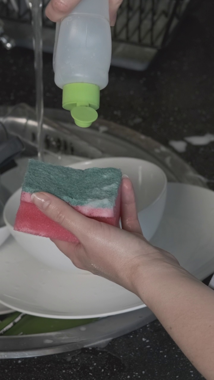 女性在厨房把洗碗皂放在海绵上视频素材