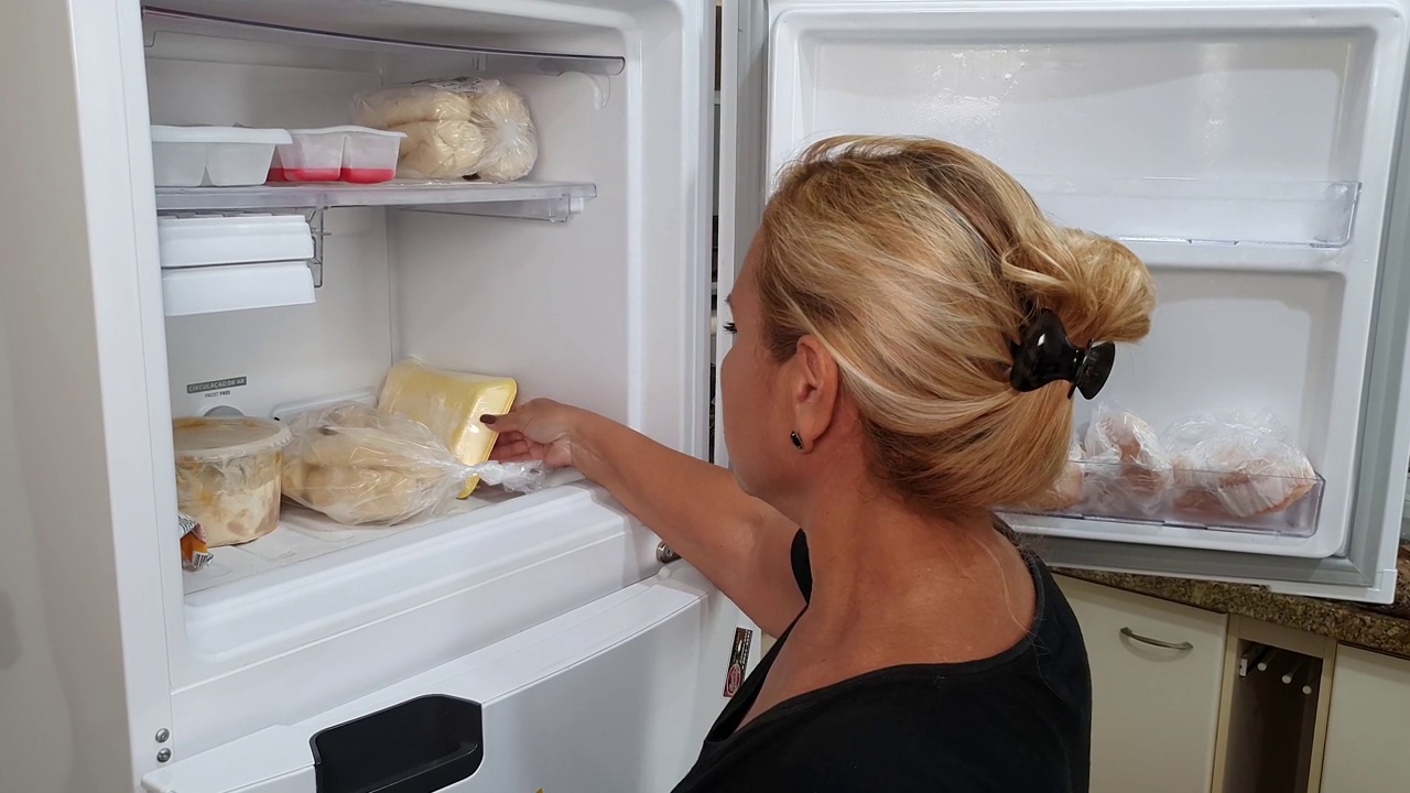 家庭主妇在冰箱里寻找冷冻面包视频素材