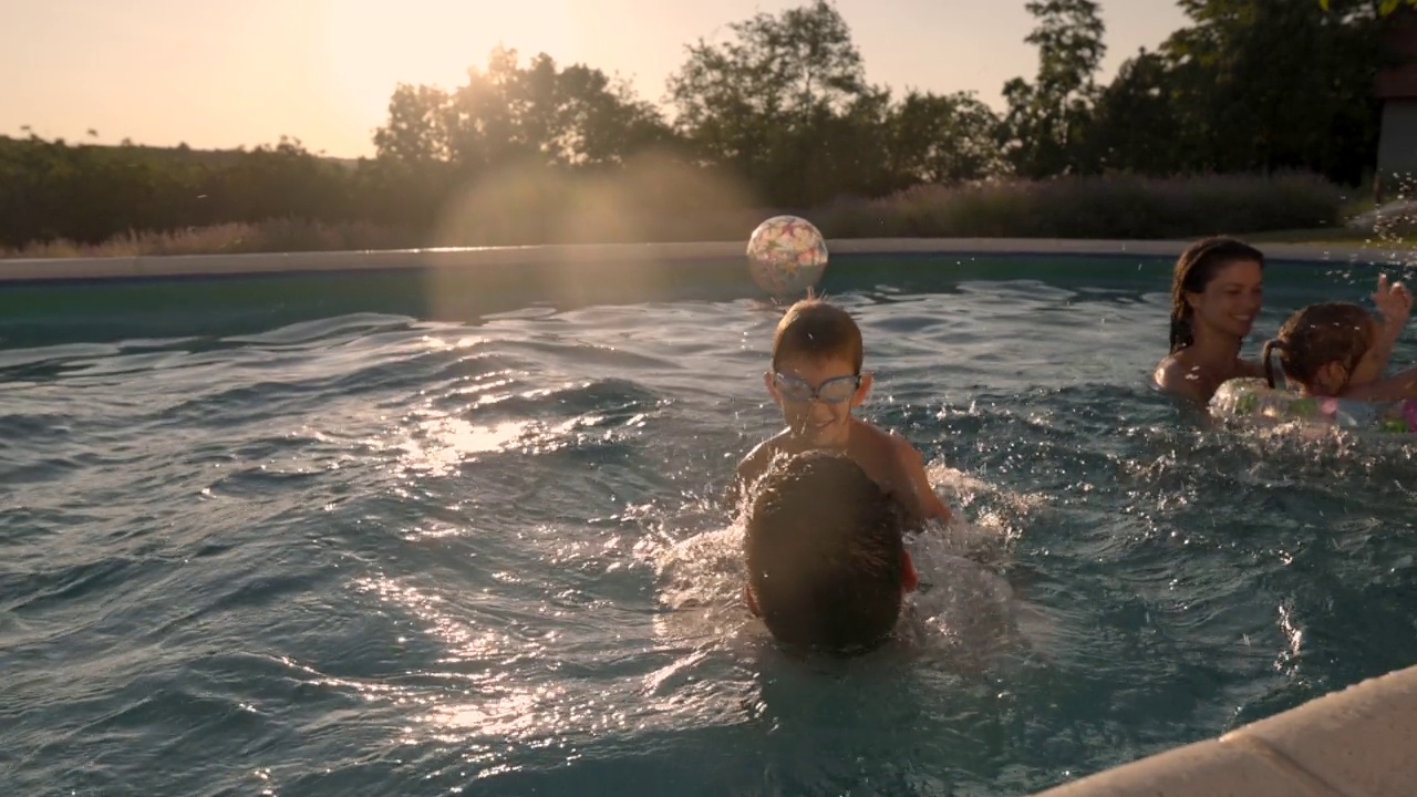 嬉戏的家庭在日落时分的游泳池里玩得很开心。视频素材