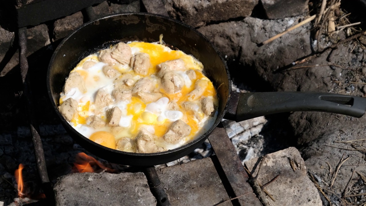 在旅游营火煎锅上用鸡肉炒蛋，自然视频素材