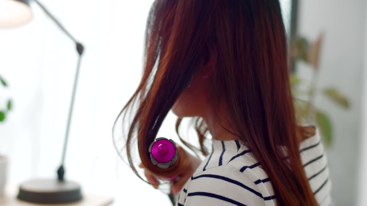 年轻女子用发刷和吹风机吹头发视频素材