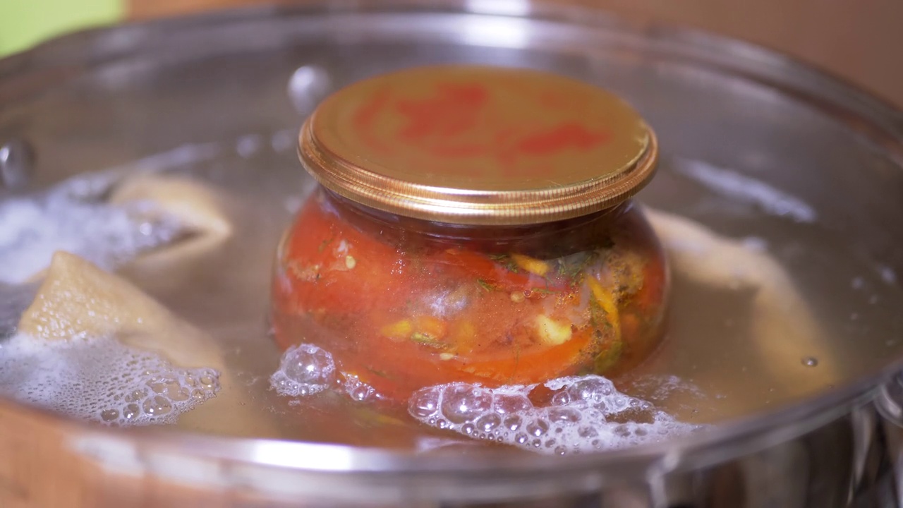 将一罐腌番茄放入沸水煮锅中消毒的过程视频下载