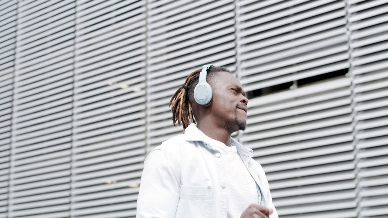 一个年轻人戴着耳机穿过城市的4k视频片段视频素材