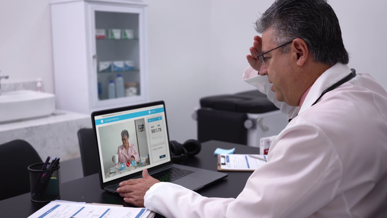 在远程医疗会诊期间，男医生在屏幕上与病人交谈视频素材