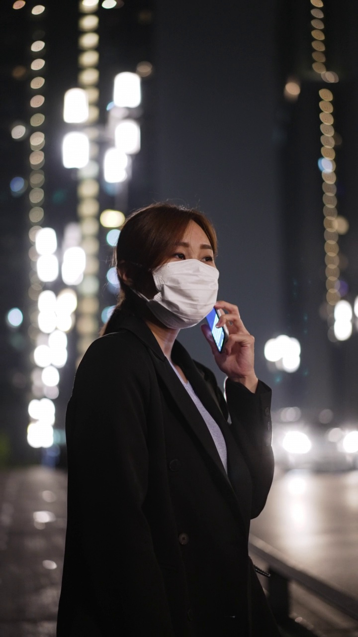 年轻的亚洲女商人深夜工作时戴着口罩打电话视频下载