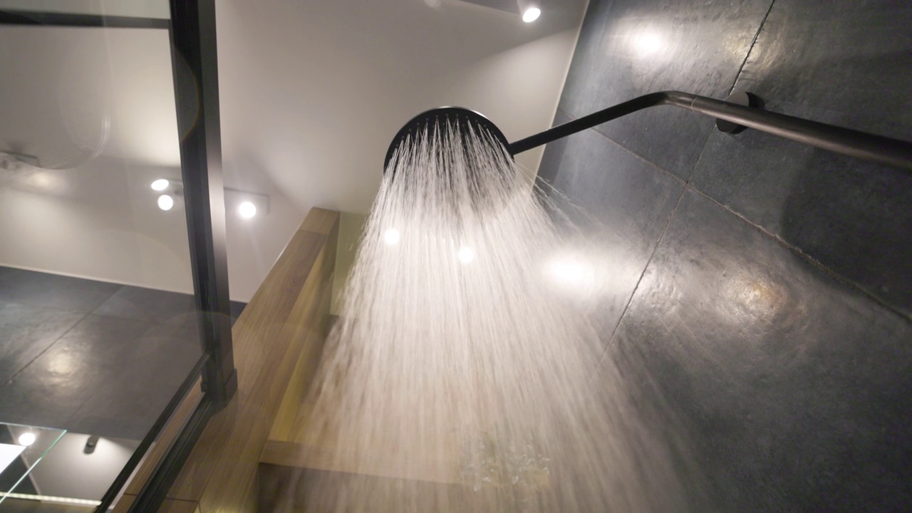 水从雨淋浴头在深蓝色现代豪华浴室。视频下载