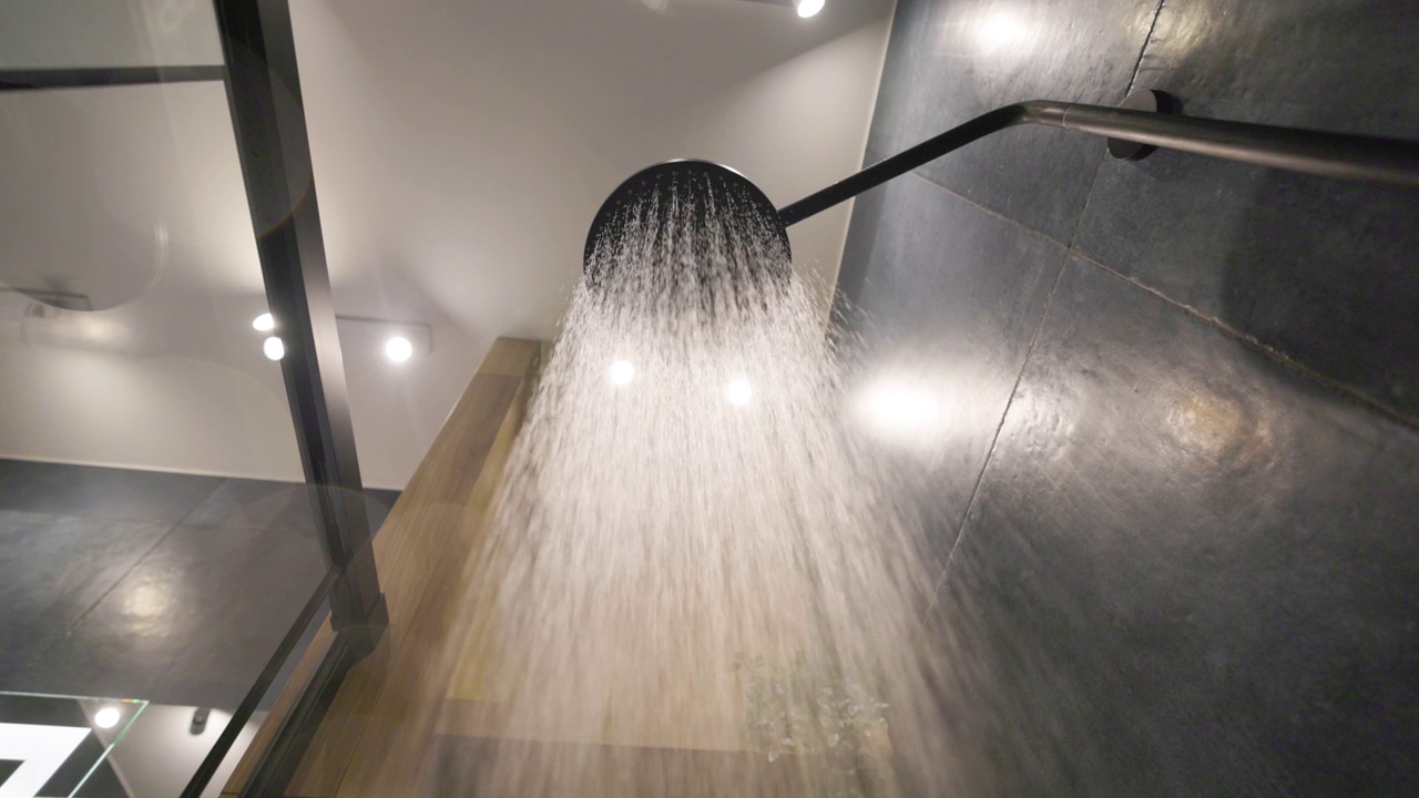 在深蓝色的现代豪华浴室里，关掉从雨淋头的水。视频下载