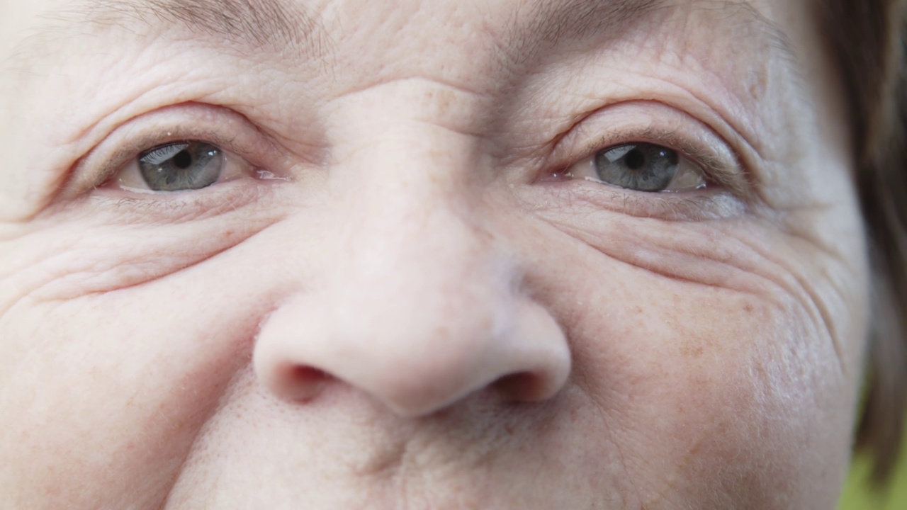 一位老年妇女的特写肖像。疲倦的眼睛周围有可爱的皱纹。视频下载