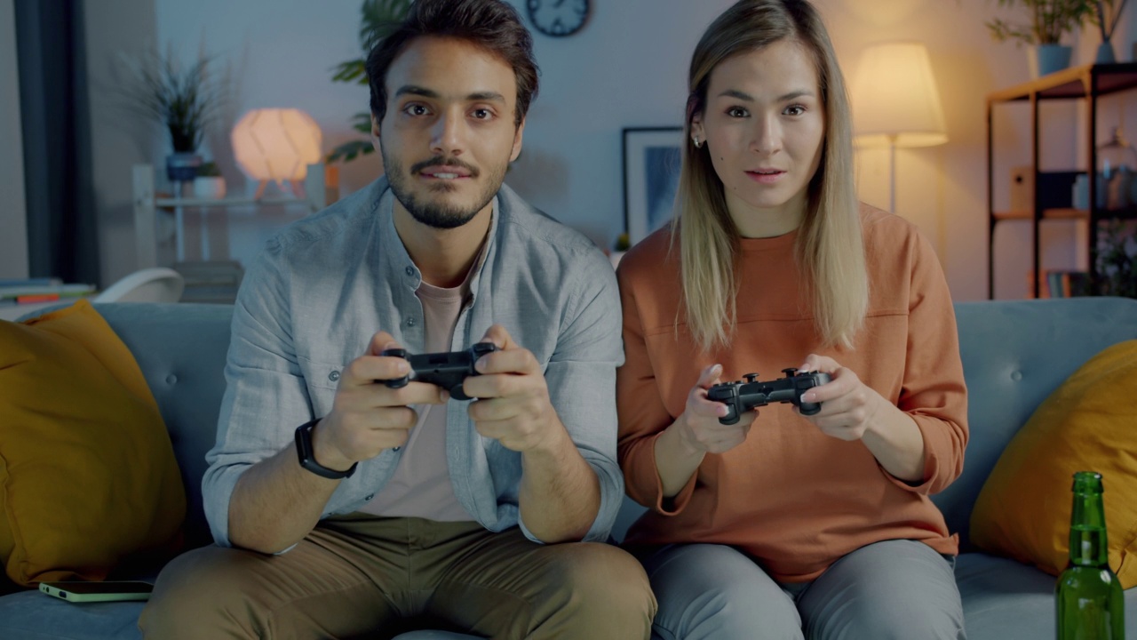 快乐的年轻夫妇晚上一起在家玩电子游戏视频素材