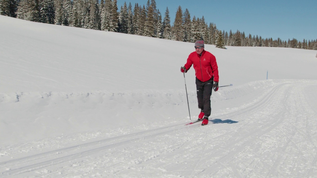 手持拍摄的越野滑雪者滑雪在“对角线步幅”方法在一个晴朗的日子在科罗拉多州的小道上上山视频下载