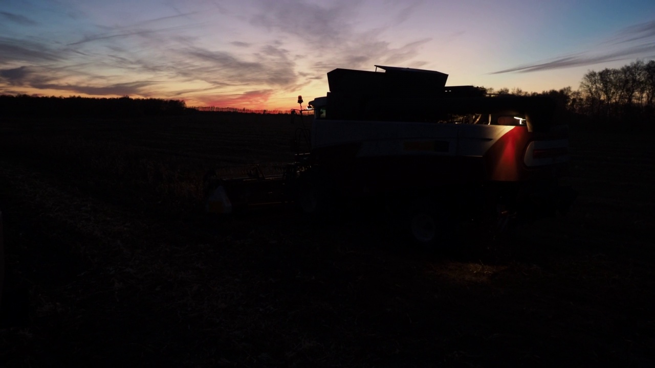 日落时分在田里工作的联合收割机视频素材