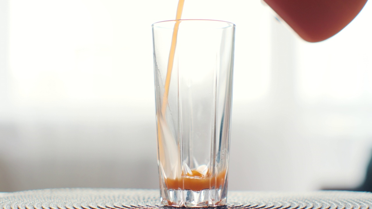 将橙汁从玻璃罐中倒入玻璃杯。健康营养，有机饮料和禁食净化理念。视频素材