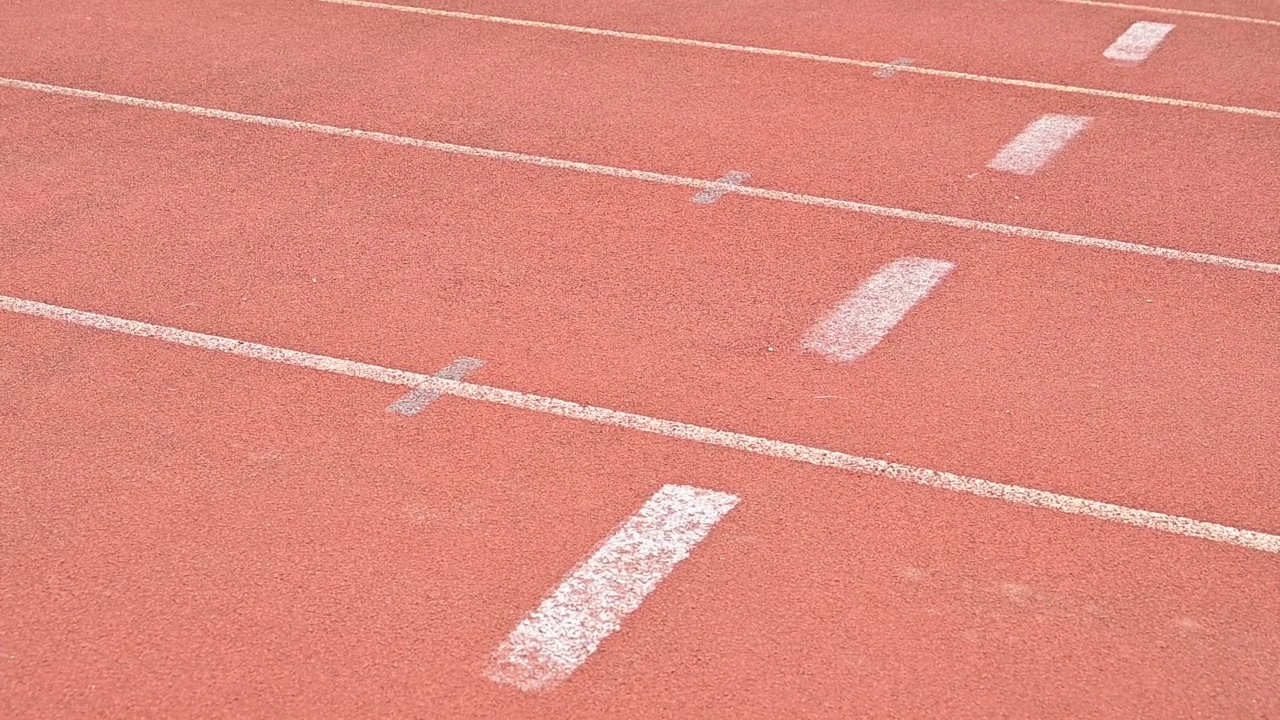 在体育场的跑道上，一名女运动员站在起跑线上准备冲刺的慢动作镜头。视频素材