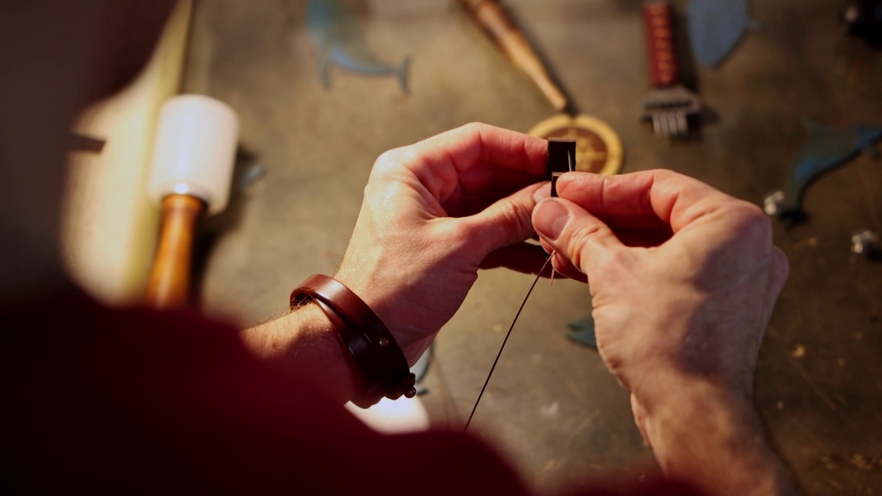 皮革车间-一个男人缝一个小的装饰皮革一块皮带视频下载