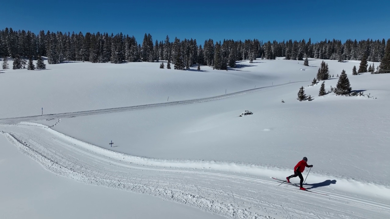 一个越野滑雪者滑雪和练习“对角步幅”方法的广角航拍在科罗拉多的Grand Mesa国家森林的修整小径上视频下载