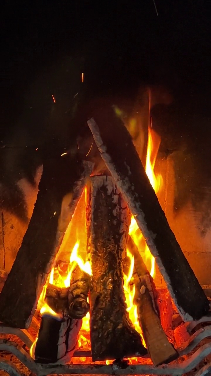 火红的余烬颜色的火焰舌头在木头上视频素材