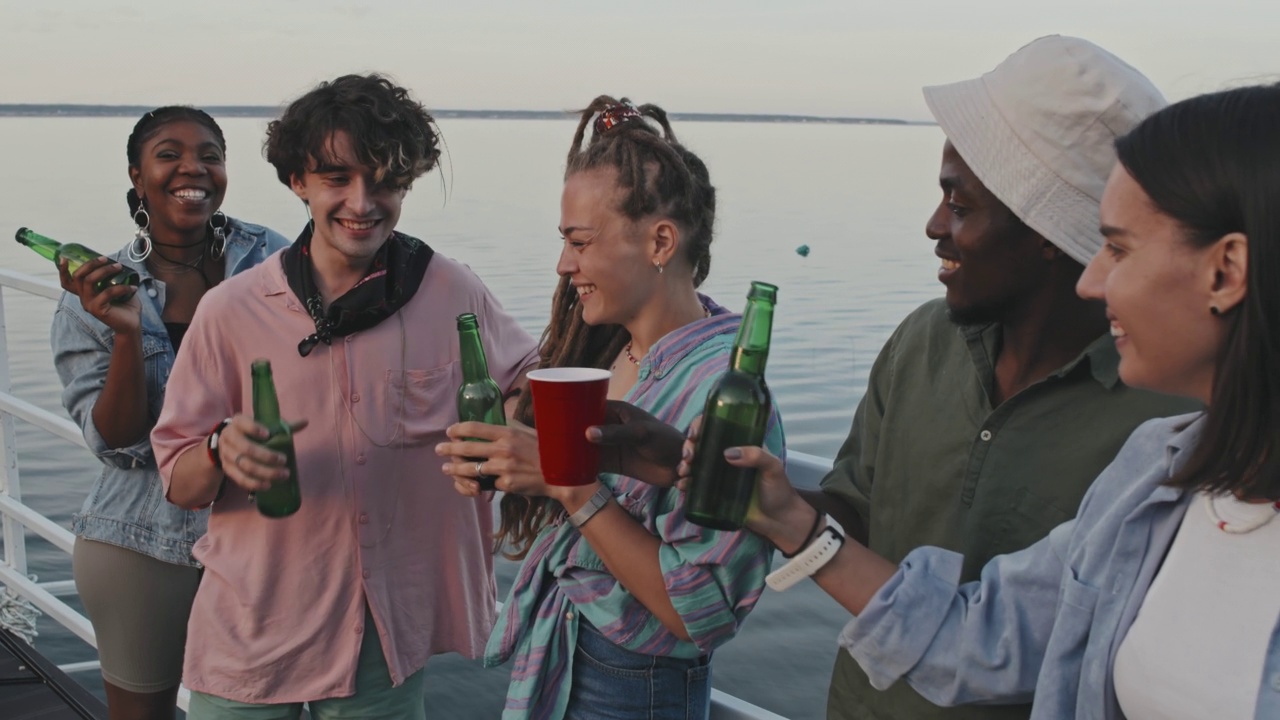 年轻的朋友在湖边喝啤酒视频素材
