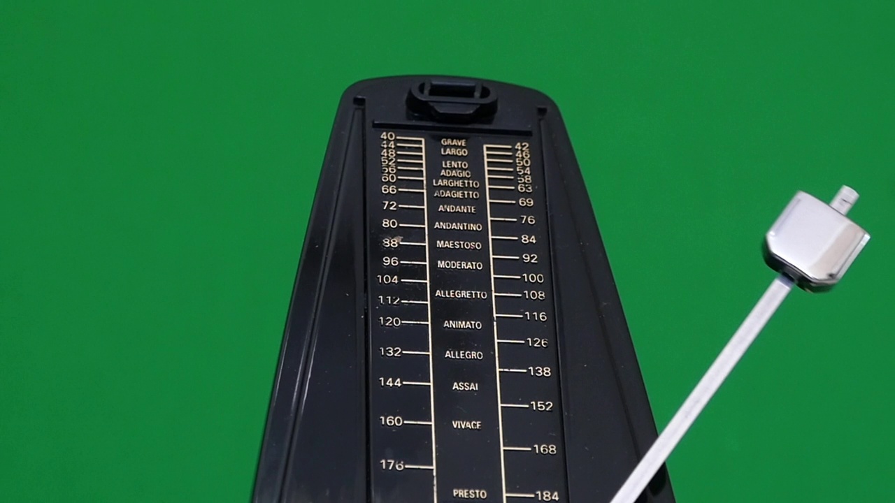 一个巨大的黑色节拍器在绿色的背景上工作视频下载