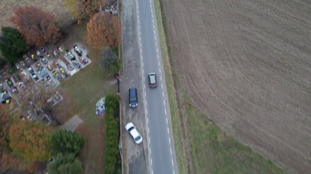 汽车正行驶在穿过田野的道路上，无人机拍下了鸟瞰图。秋天的时候在柏油路上，镜头跟着车走。视频下载