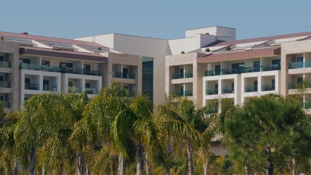 现代建筑的豪华度假酒店和花园热带棕榈树，阳光明媚的夏日视频下载