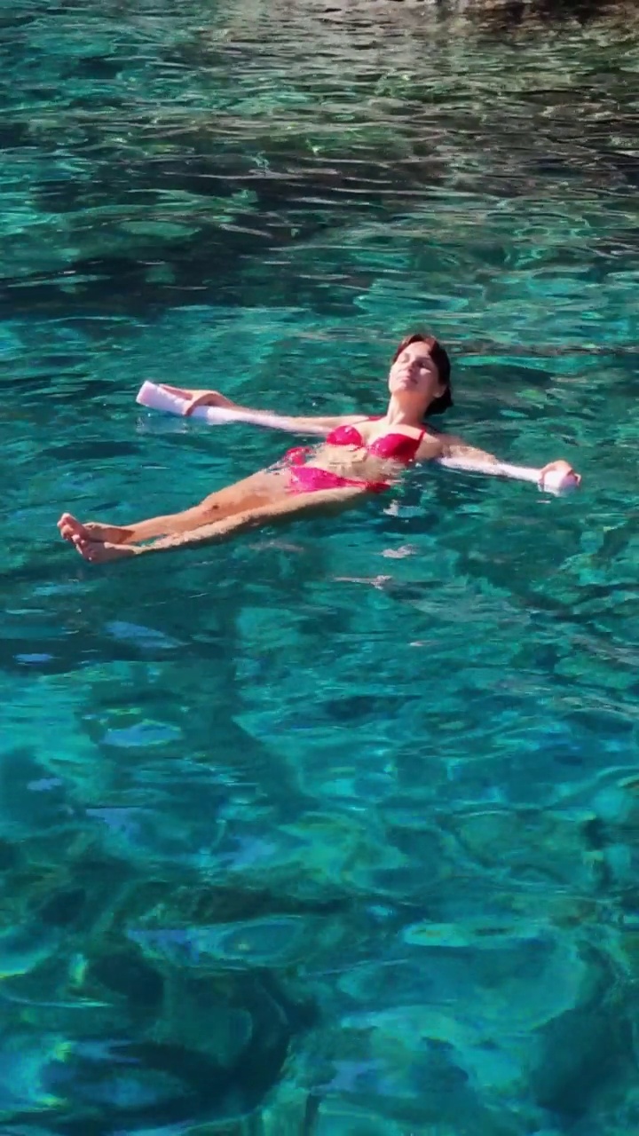 一名年轻女子坐在泡面上慢动作地浮在海面上视频下载