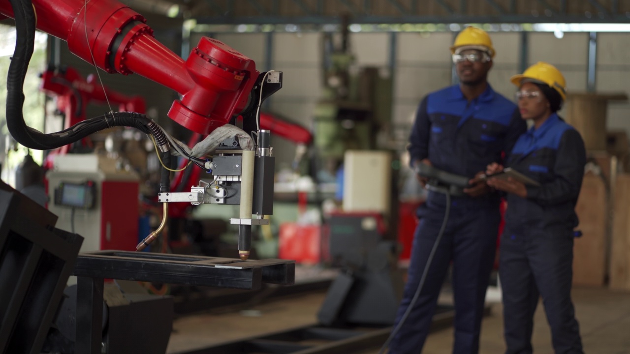 非洲男性和女性工程师在自动化工厂编程工业机器人视频素材
