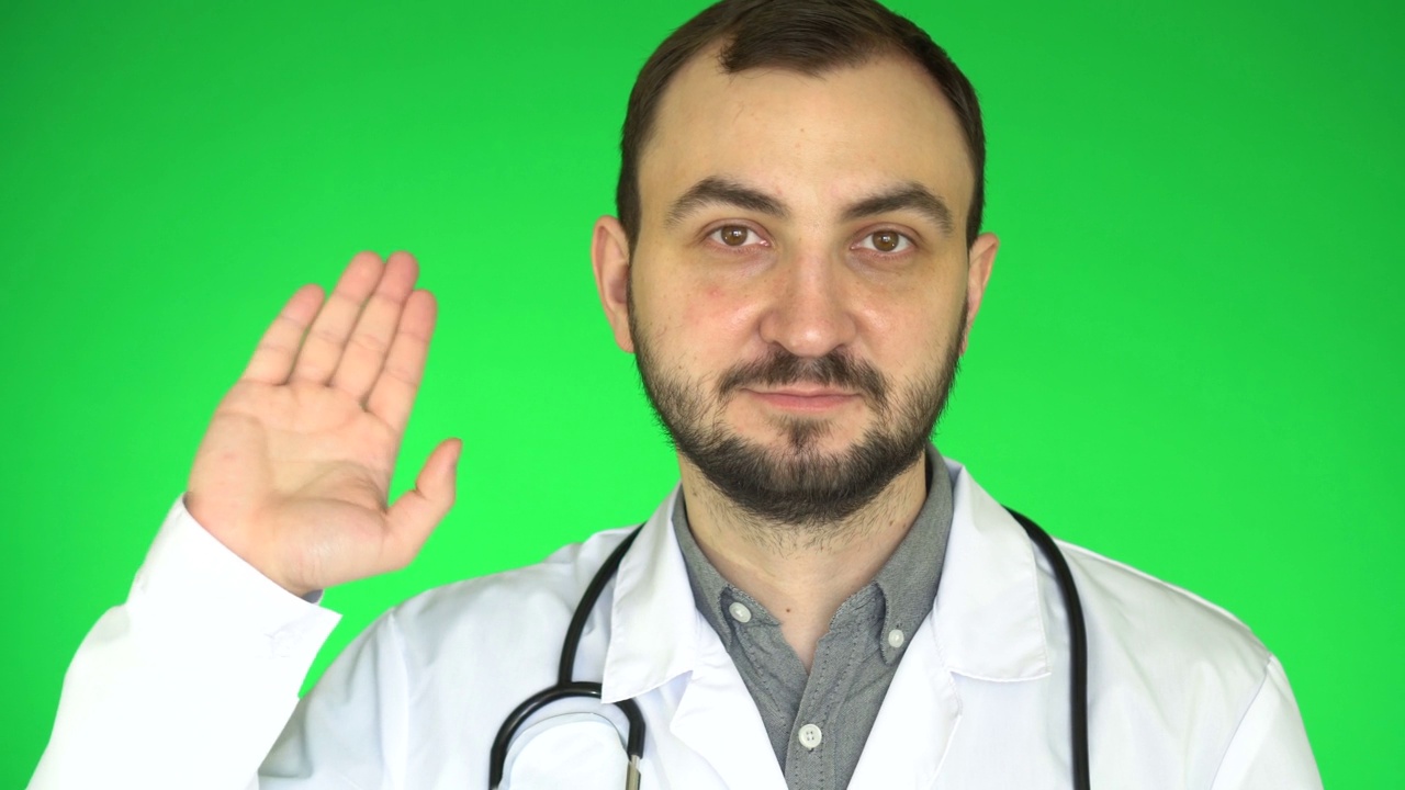 医生看着镜头，挥手致意。绿屏背景视频下载