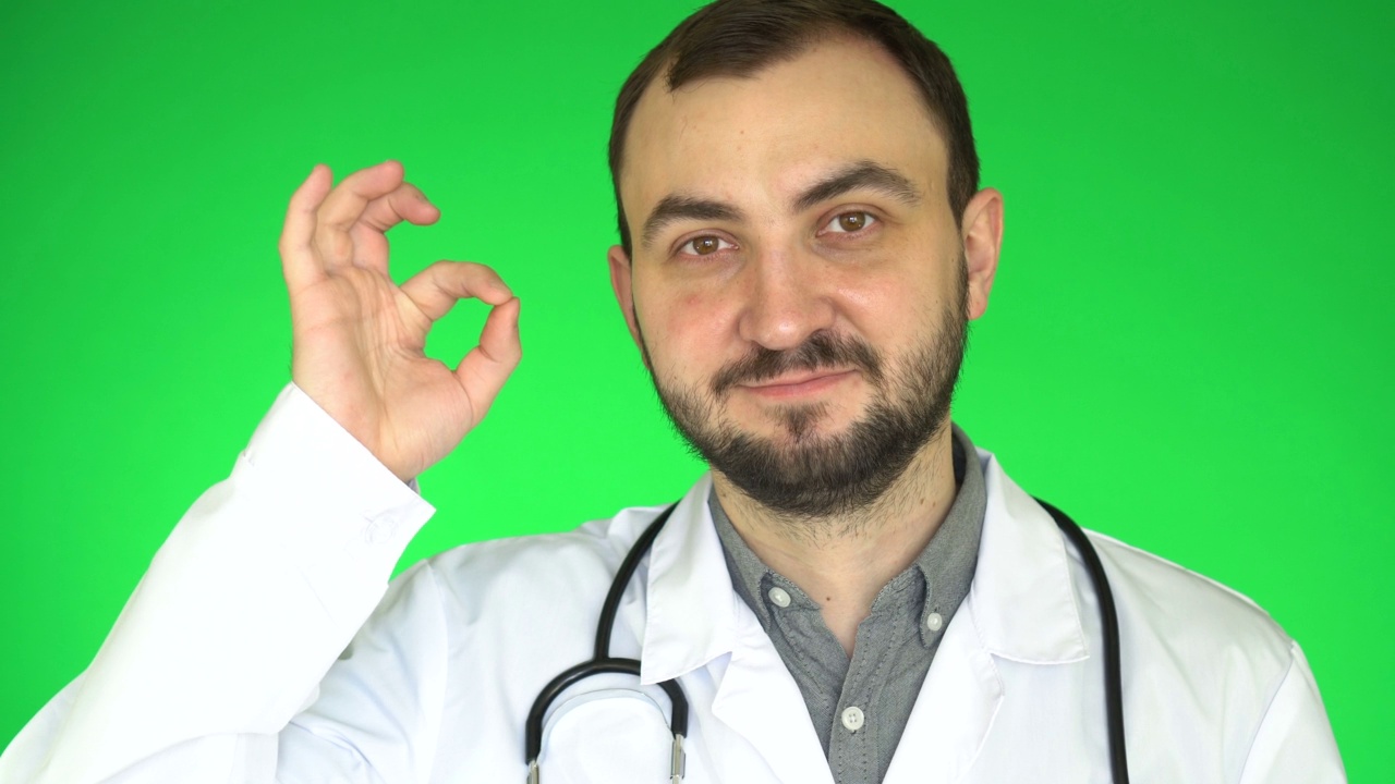 医生看着摄像机，并表现出良好的姿态。绿屏背景视频下载
