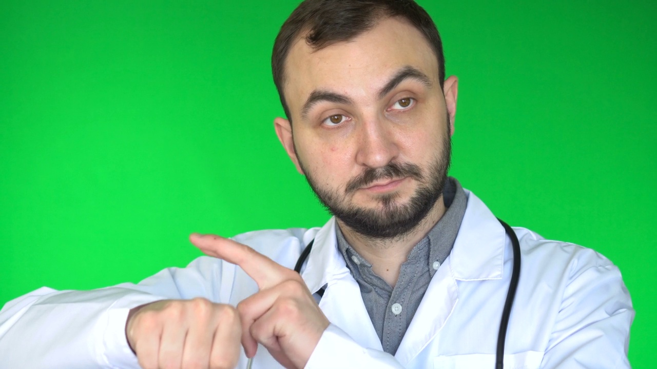 医生看着相机，举起手臂轻拍手表。绿屏背景视频下载