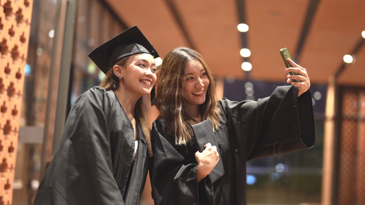 亚洲十几岁的女孩穿着毕业礼服布带着心情开心。穿黑色毕业礼服的人持有毕业证书。视频下载